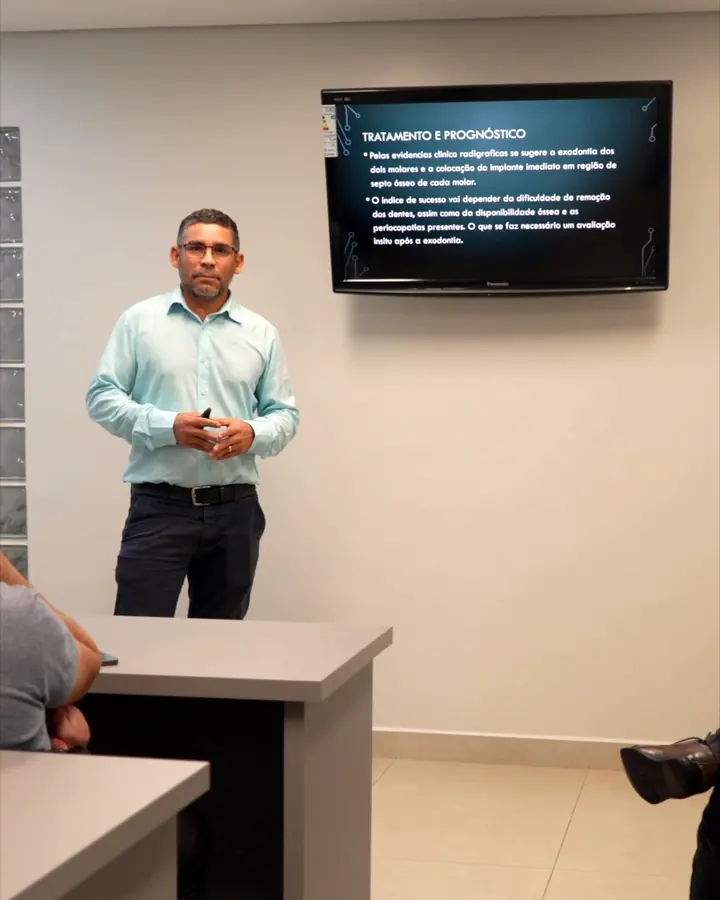 Docente en clase expositiva con presentación en pantalla